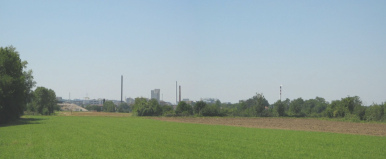 Pratteln: Netzibodenstrasse, ARA Rhein,
                        Sicht auf das Feld mit den Kaminen der
                        Giftfabriken von Schweizerhalle am Horizont,
                        Panoramafoto