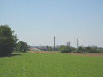 Pratteln: Netzibodenstrasse, ARA Rhein,
                        Sicht auf das Feld mit den Kaminen der
                        Giftfabriken von Schweizerhalle am Horizont 01