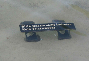Basel, Tinguelybrunnen, Schild, dass man
                      nicht in den Brunnen steigen soll ("Bitte
                      Bassin nicht betreten"), und "Kein
                      Trinkwasser"