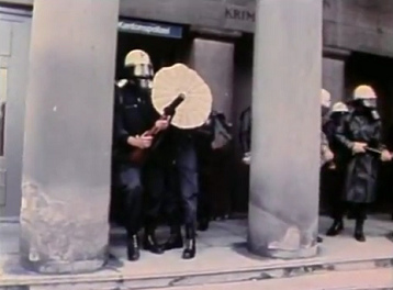 Schlgerpolizei mit
                        Trnengaspistolen zwischen den Sulen beim
                        "Polizeiposten Limmatquai", 18.6.1980