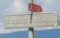 Corcelles, Strassenschild der Strasse
                          "Chemin derrire chez Chapuis" beim
                          Bahnbergang